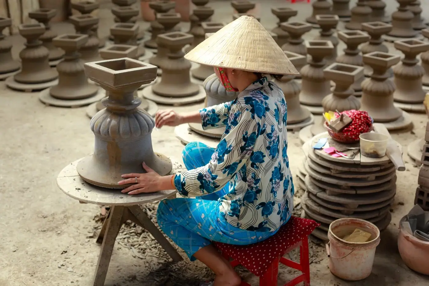 Artisan in traditional dress throwing clay on a pottery wheel in Bat Trang village