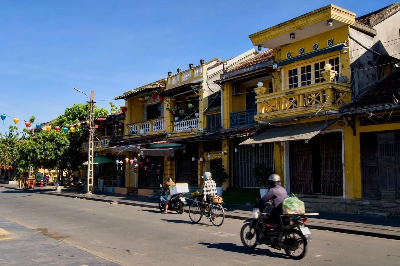 Locals riding motorbikes and bicycles on a quiet Hoi An street