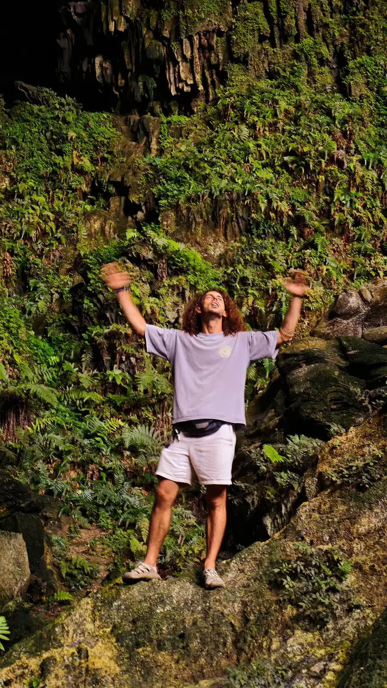 Traveler celebrating inside a moss-covered limestone cave near Trang An, Ninh Binh