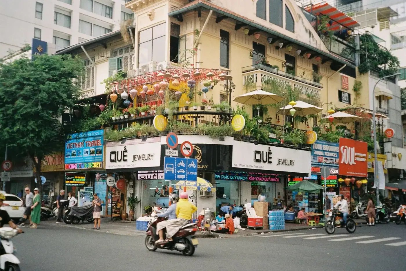 Scooters passing green-covered buildings on a Da Nang street