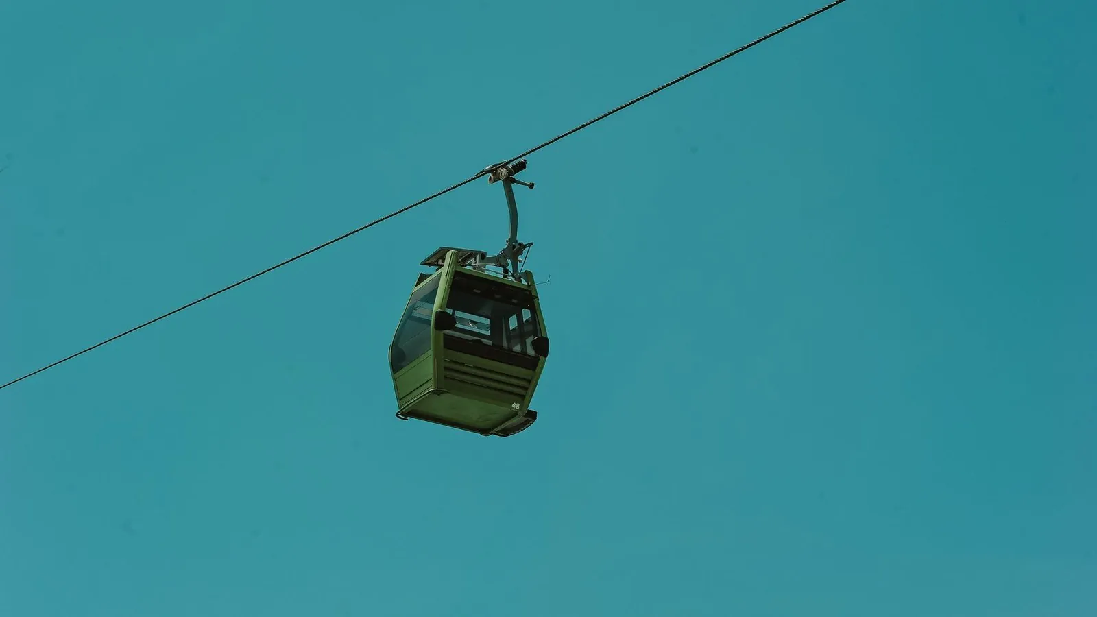 A cable car gondola suspended against a clear turquoise sky