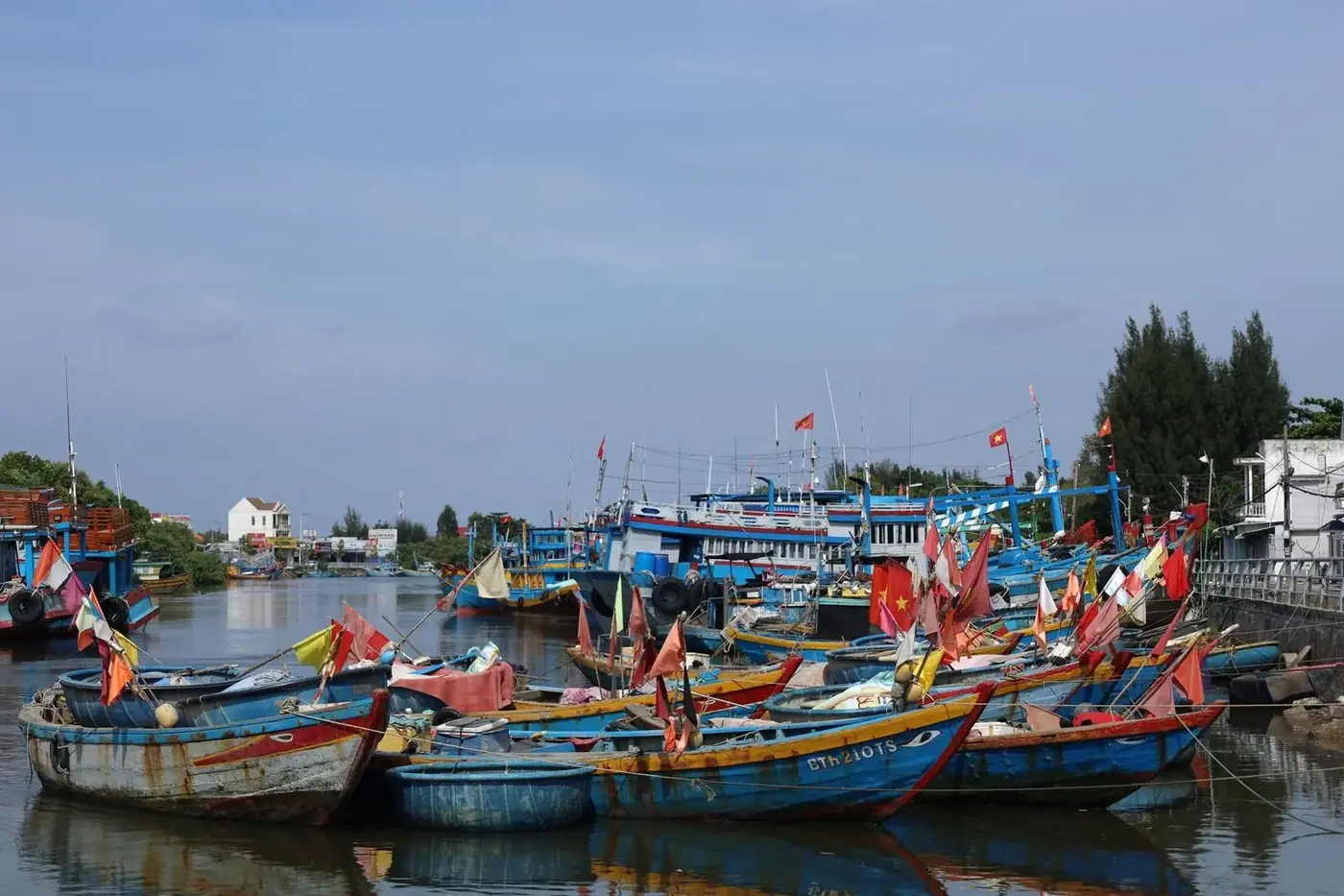 Traditional wooden fishing boats decorated with Vietnamese flags docked in a harbor