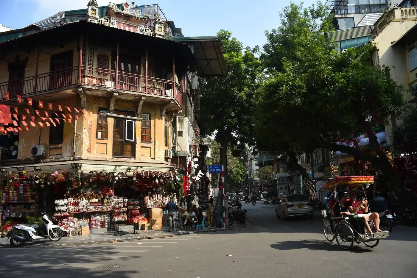 A cyclo and Vietnamese flags on a street in Hanoi Old Quarter