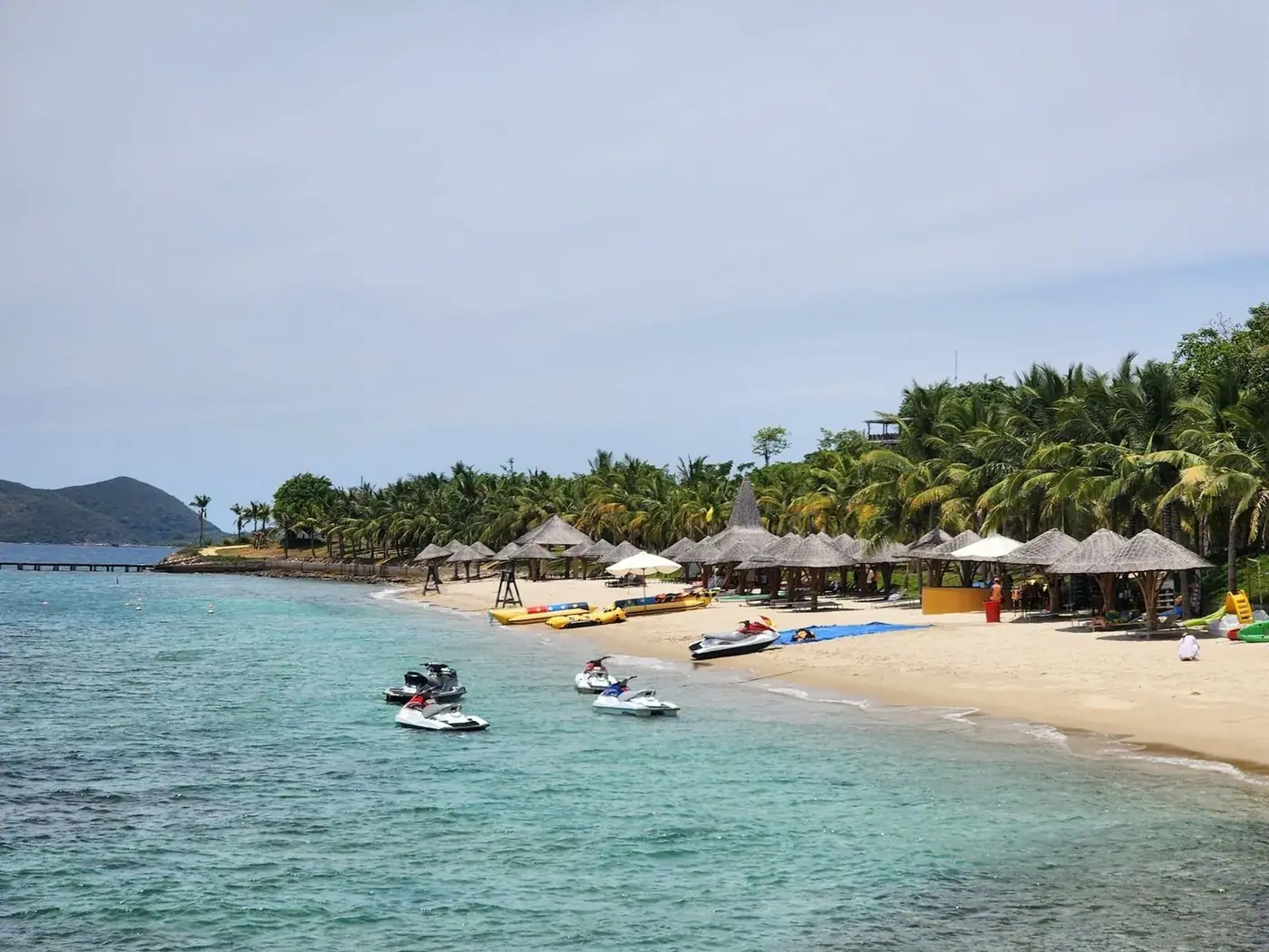 Jet skis and thatched beach huts on a quiet island shore