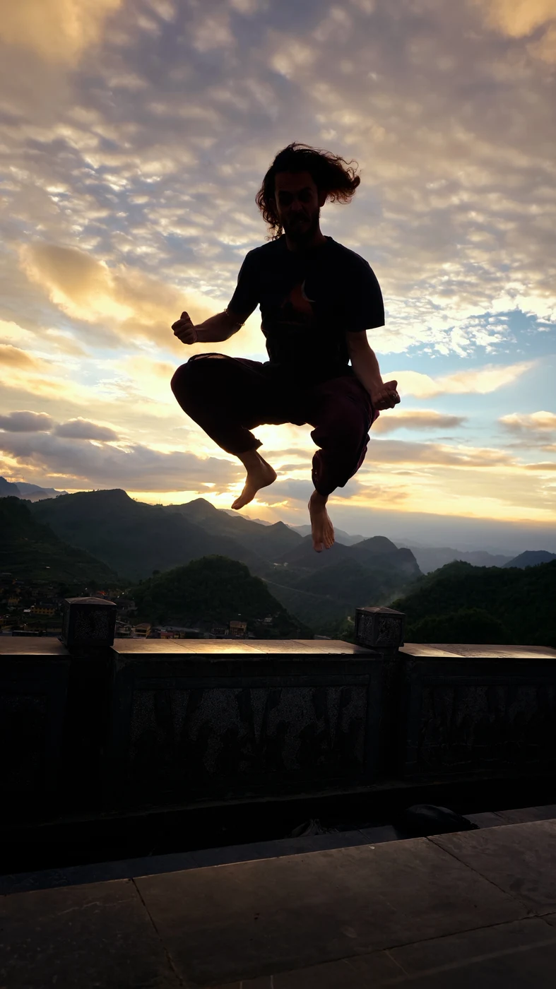 Traveler captured mid-jump in silhouette against a golden sunset sky