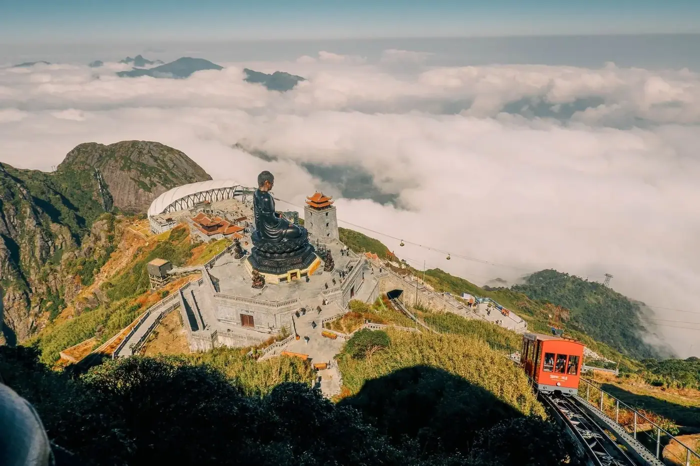 Fansipan cable car arriving at the summit station above a sea of clouds with a large Buddha statue