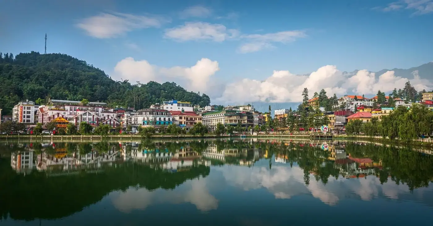 Sapa town center reflected in a calm lake surrounded by hillside hotels