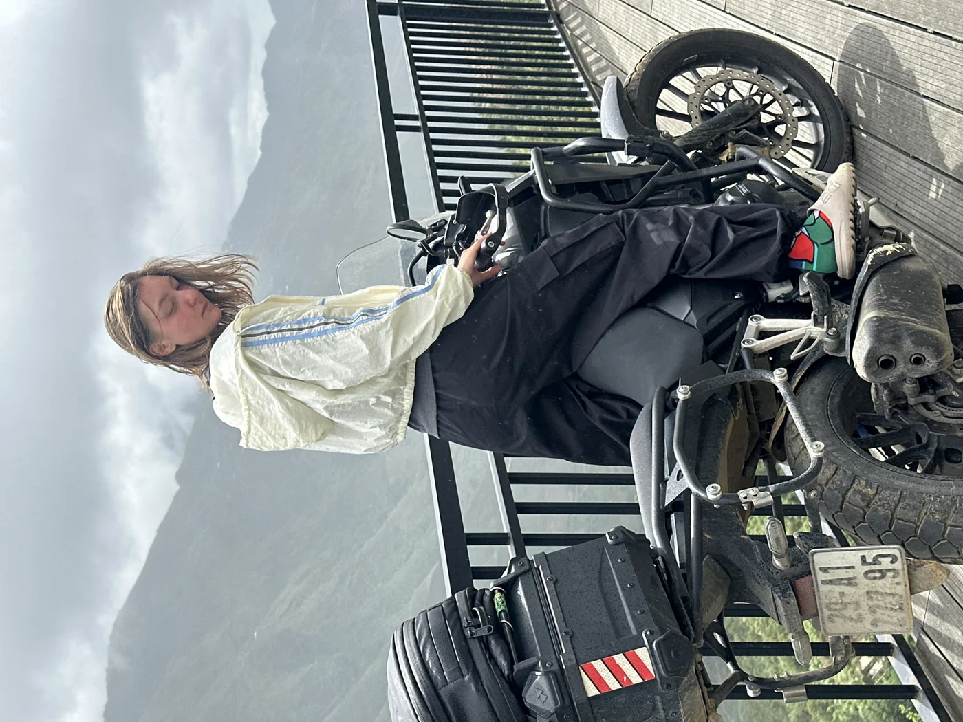 Traveler getting on a rented Honda at a misty mountain viewpoint