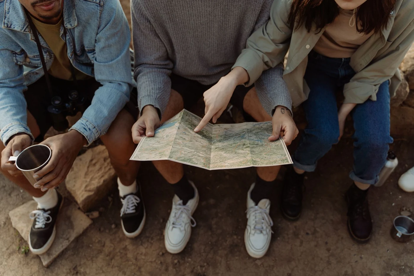 Travelers sitting together and reviewing a paper map to plan a route.