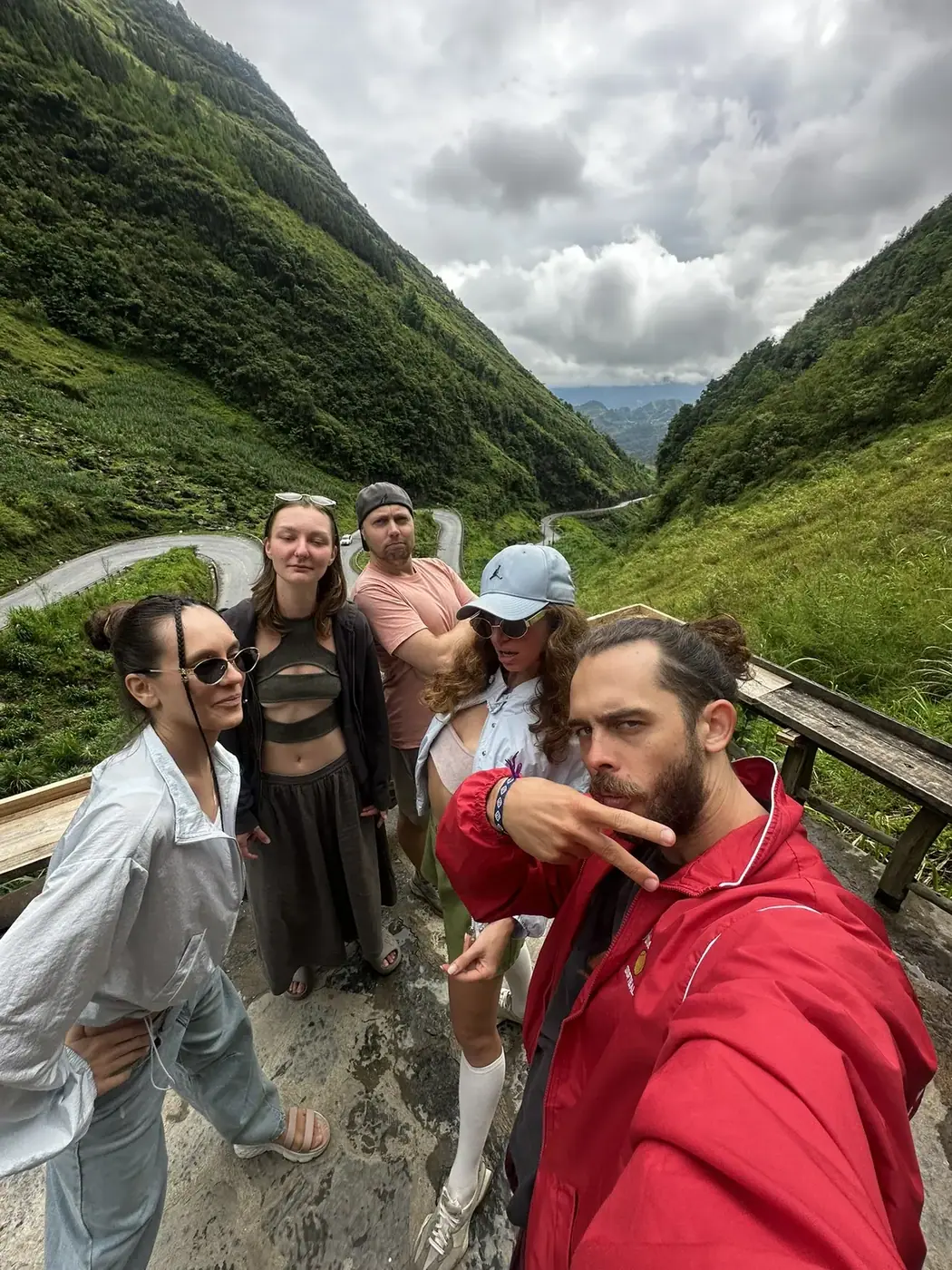 A group of travelers at a mountain viewpoint above the Ha Giang loop’s switchback road