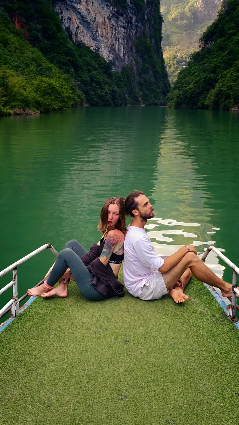A boat on the emerald Nho Que river between karst cliffs