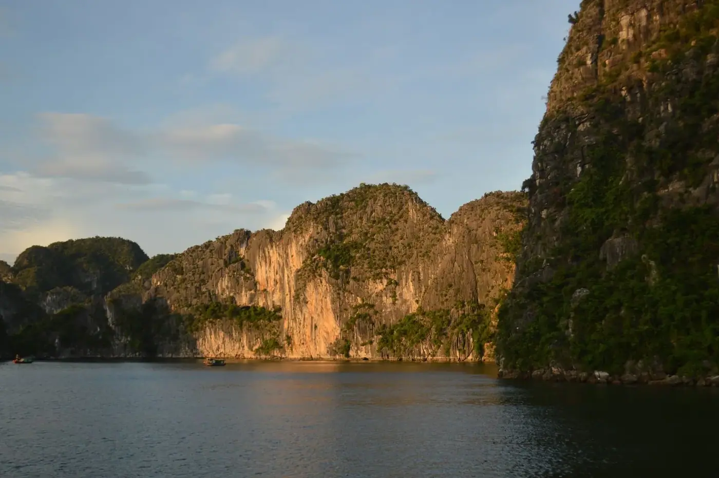 Golden hour light on Ha Long Bay limestone cliffs seen from a cruise deck