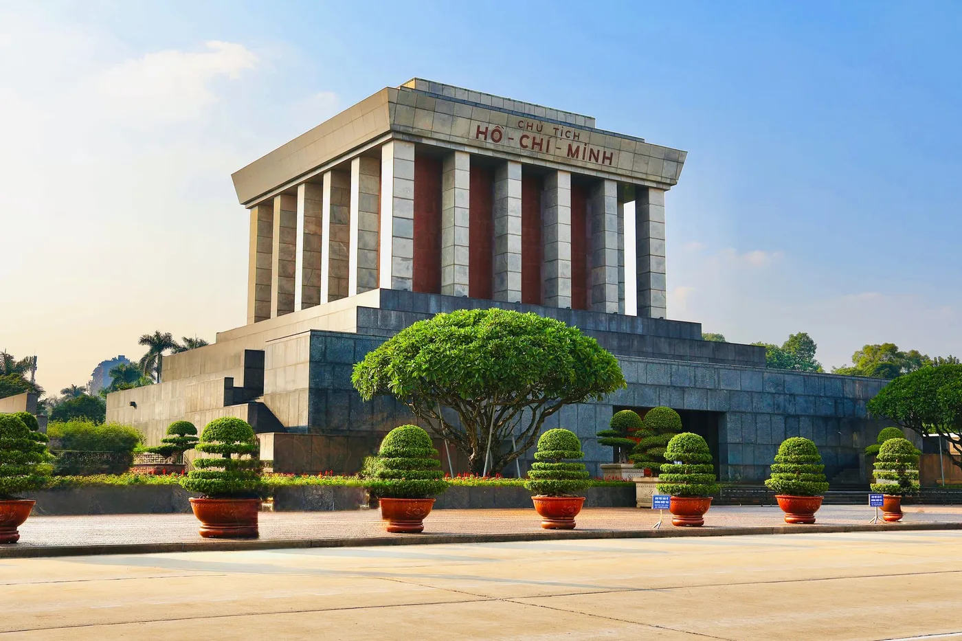 Ho Chi Minh Mausoleum facade with manicured trees lining the entrance