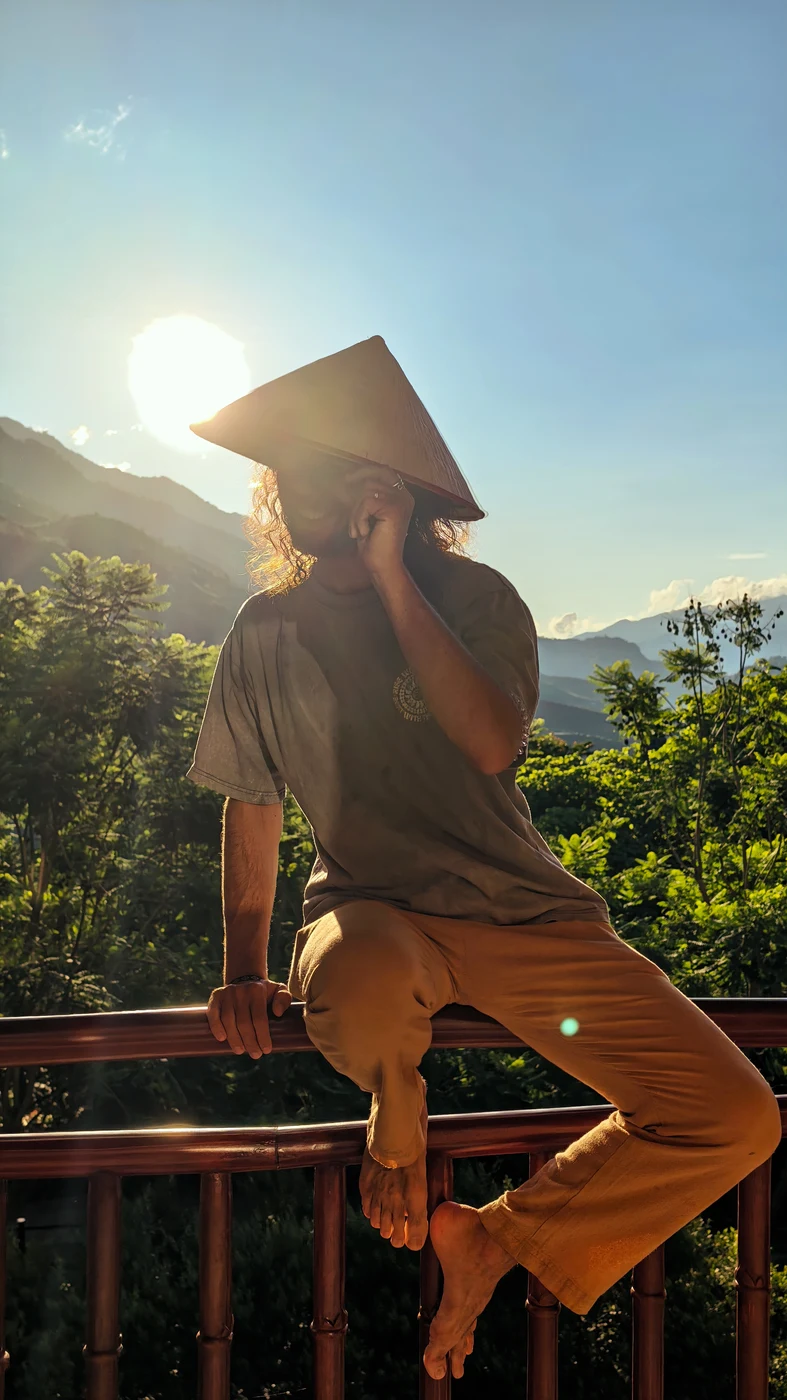 Silhouette of a traveler in a conical hat against golden sunlight
