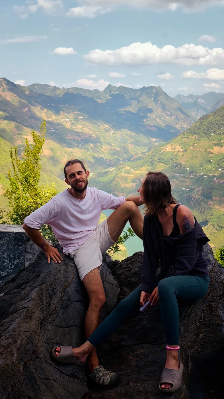 Couple sitting on a rock overlooking green mountain terraces