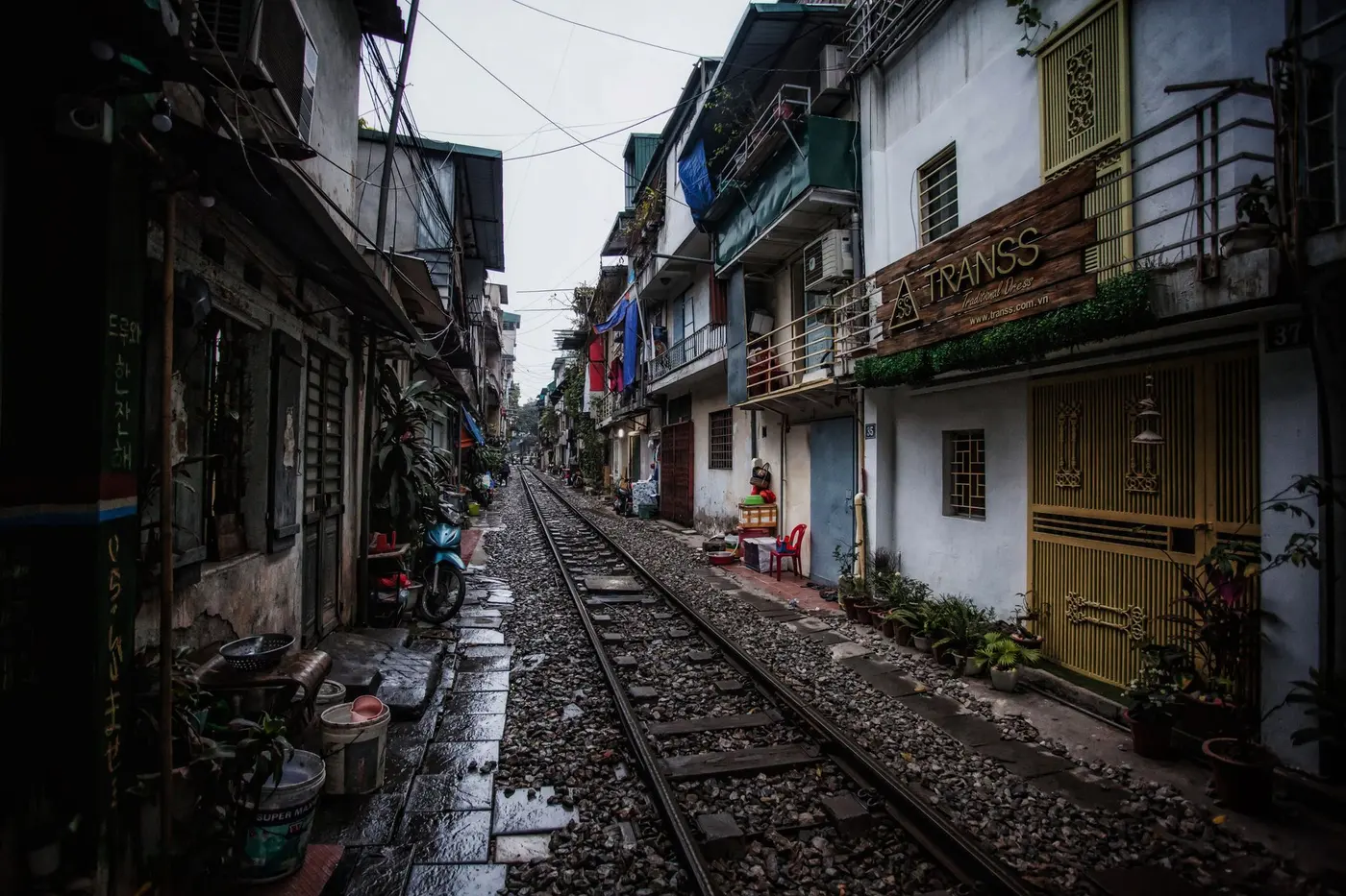 Narrow Hanoi street running along wet railway tracks