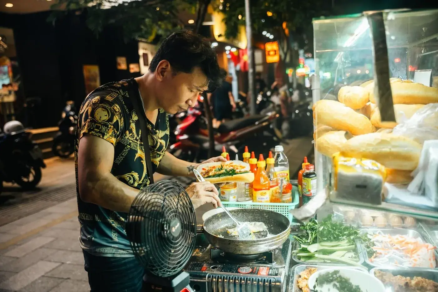 Street vendor preparing banh mi at a night food stall in Vietnam