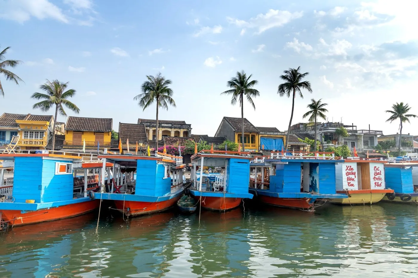 Colorful boats moored on the Thu Bon River in front of Old Town houses