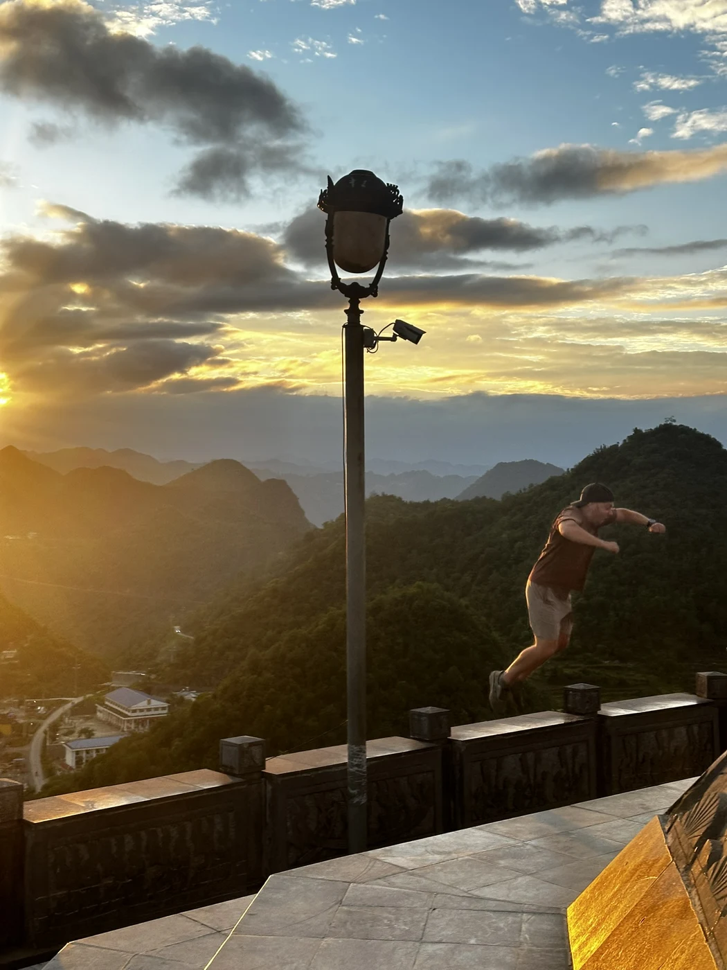Silhouette of a traveler leaping off a ledge at golden hour