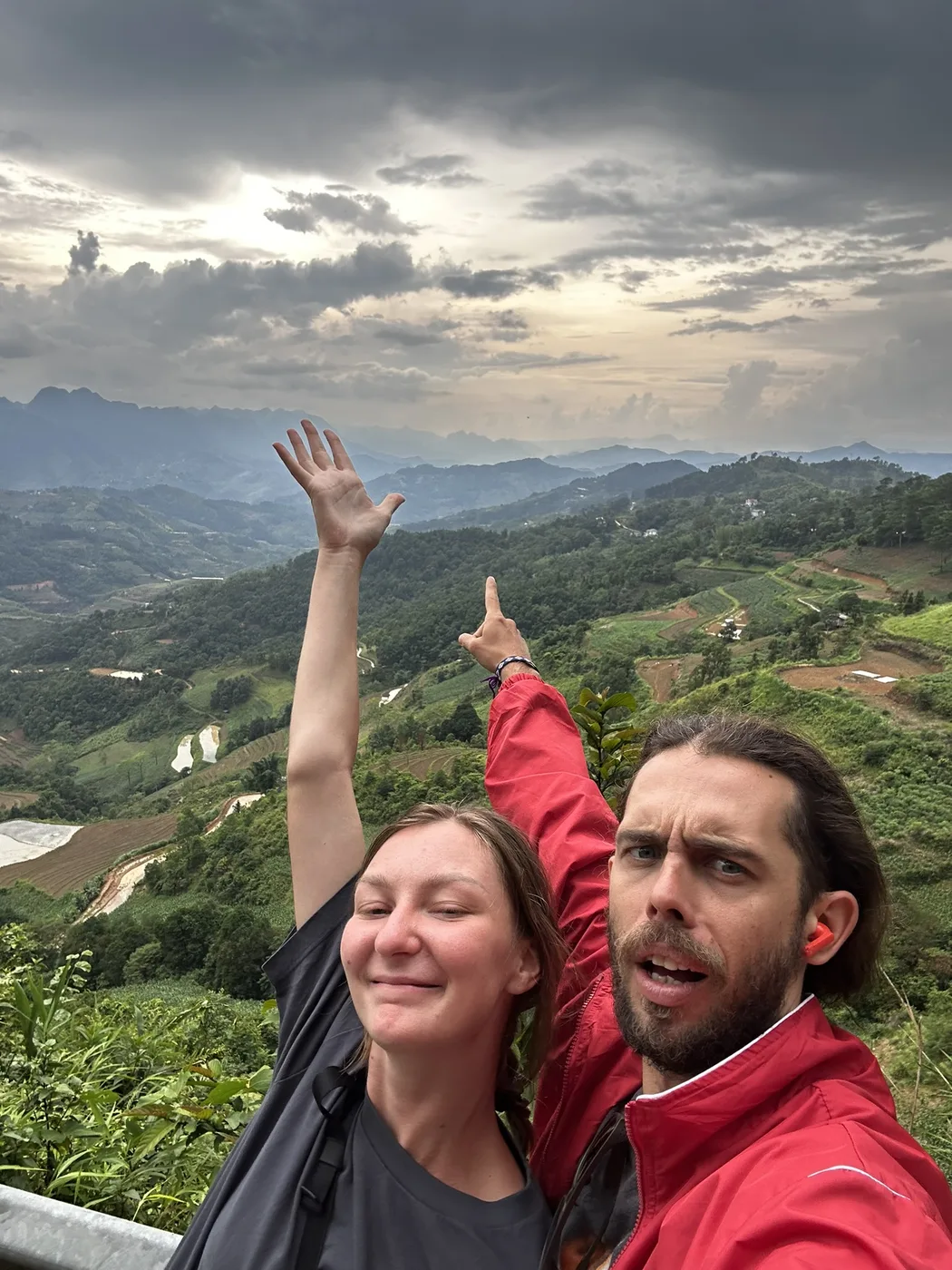 Couple cheering with raised arms above a green terraced valley