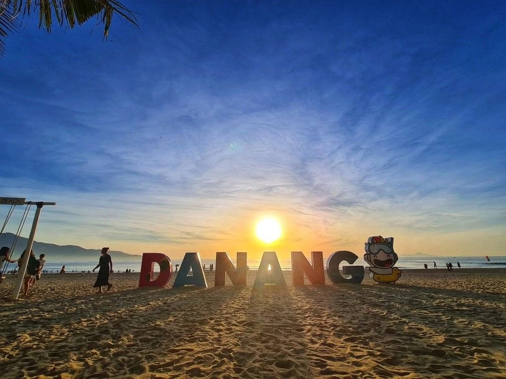 sunset over a coastal beach with a city sign on the sand