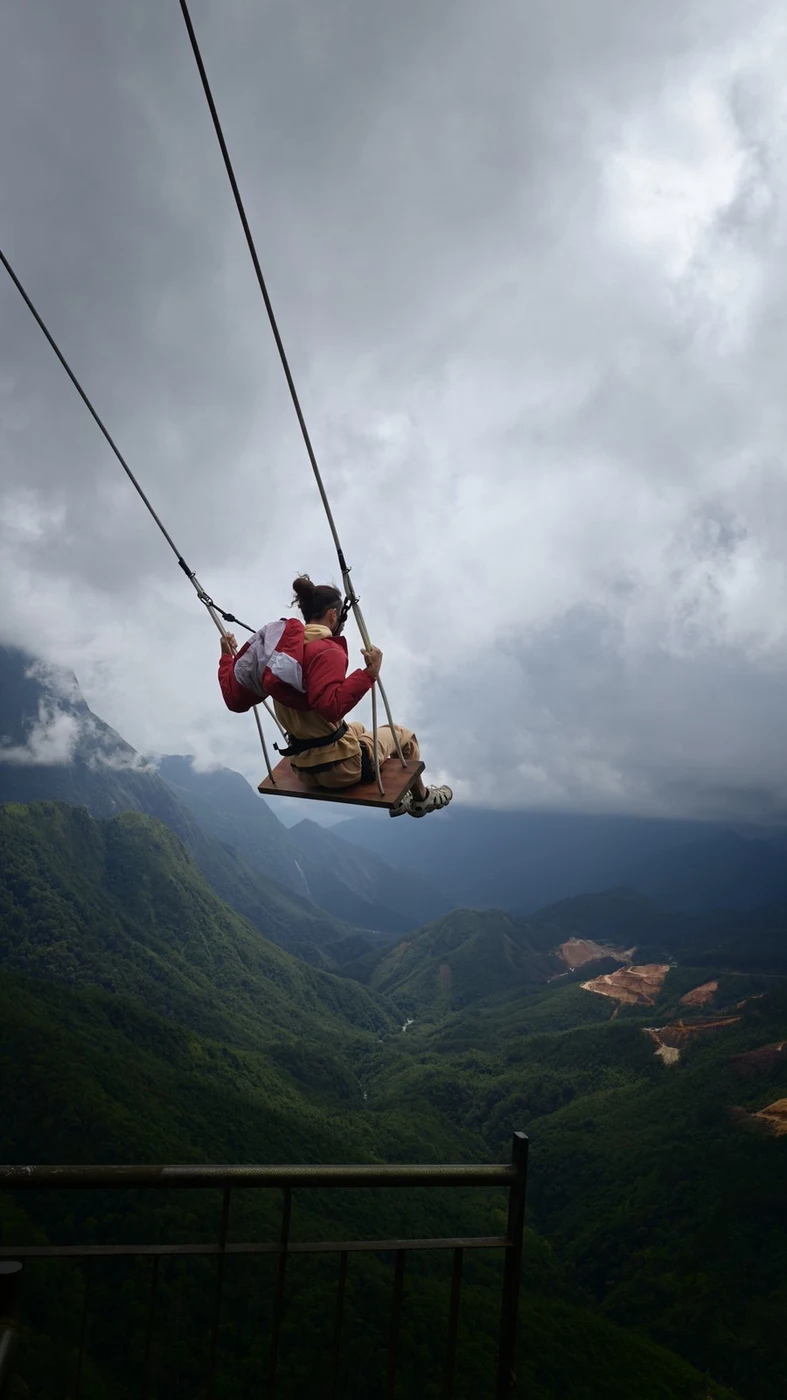 traveler on a cliffside swing above northern mountains