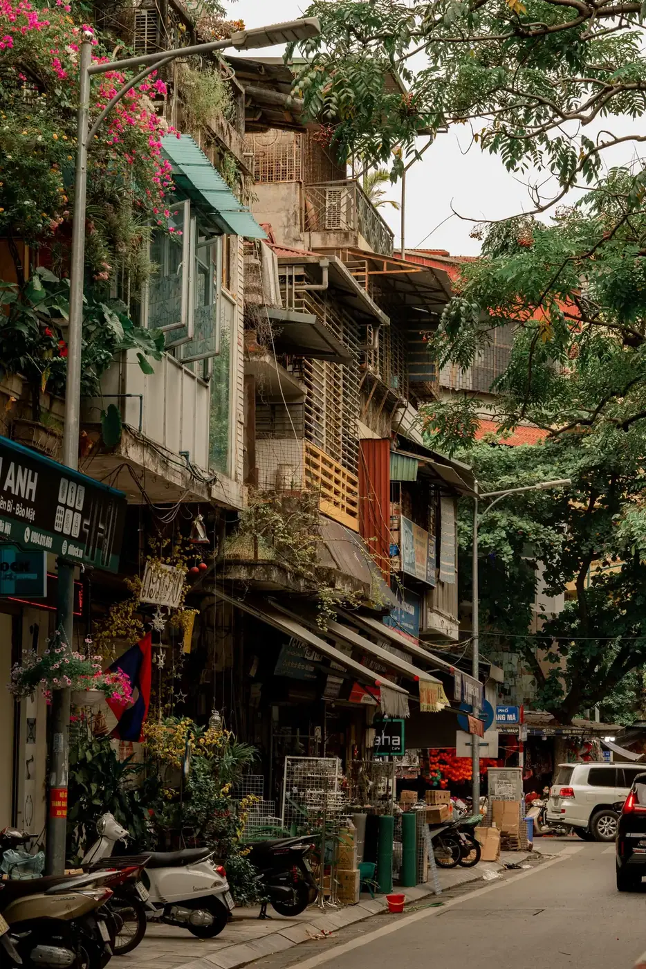 Narrow Hanoi Old Quarter street lined with balconies, shopfronts and hanging plants