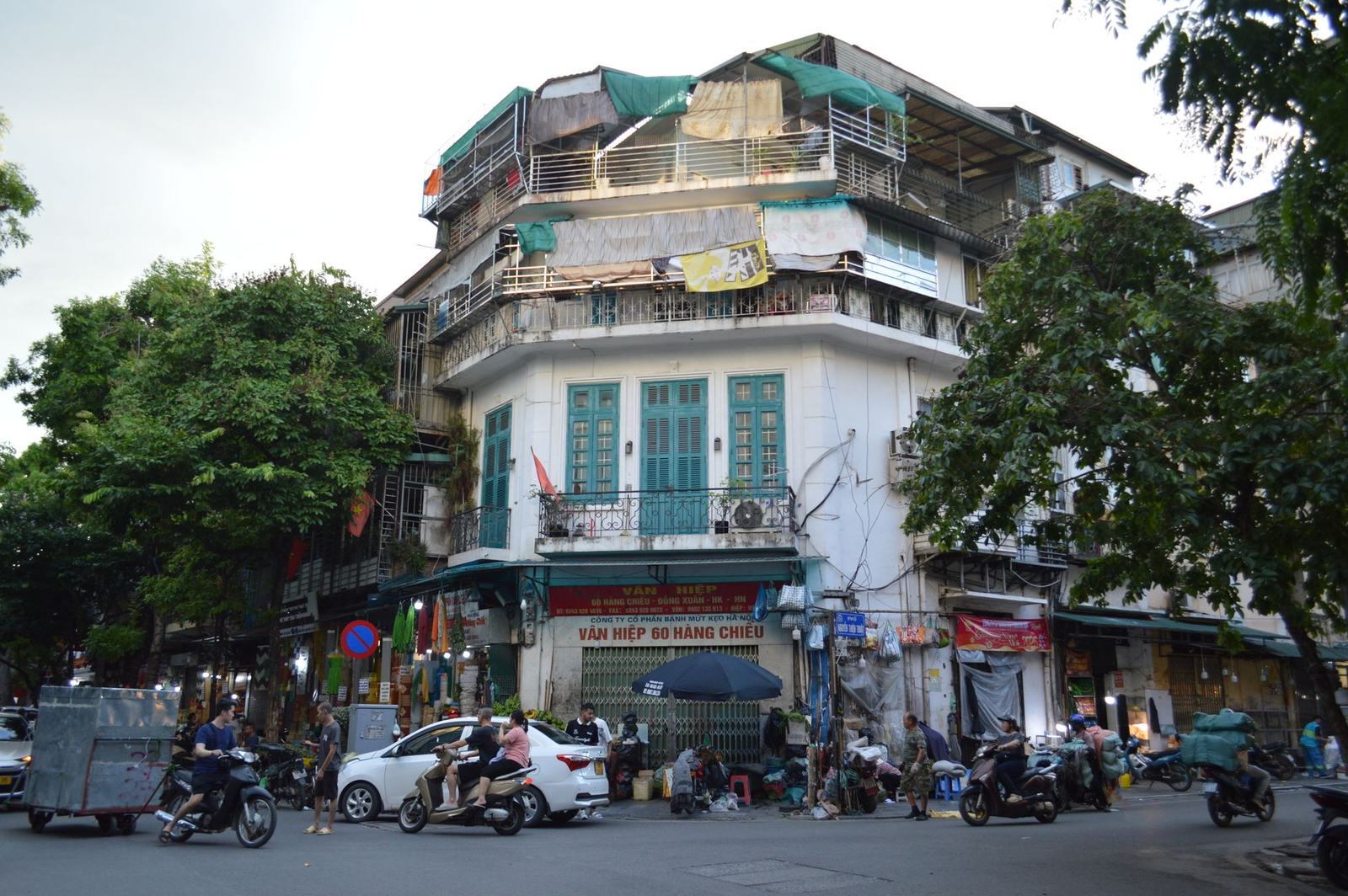 Motorbikes passing a colonial-era corner building in Hanoi’s Old Quarter