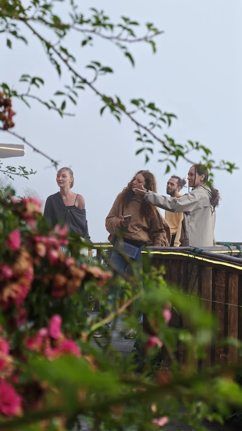 Group of travelers on a viewpoint terrace with flowers in the fog