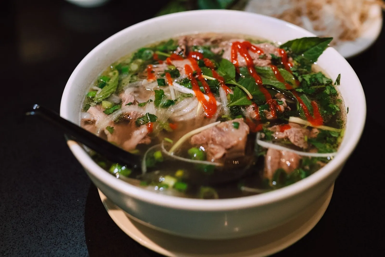 Bowl of traditional Vietnamese pho with fresh herbs and clear broth