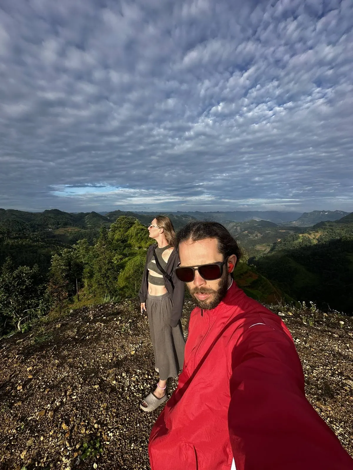 Two travelers on a viewpoint overlooking the Ha Giang loop mountains