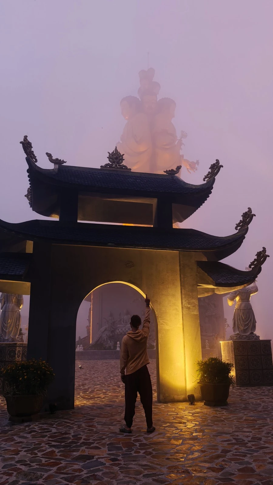 Person standing at a foggy temple gate in the mountains near Sapa, Vietnam