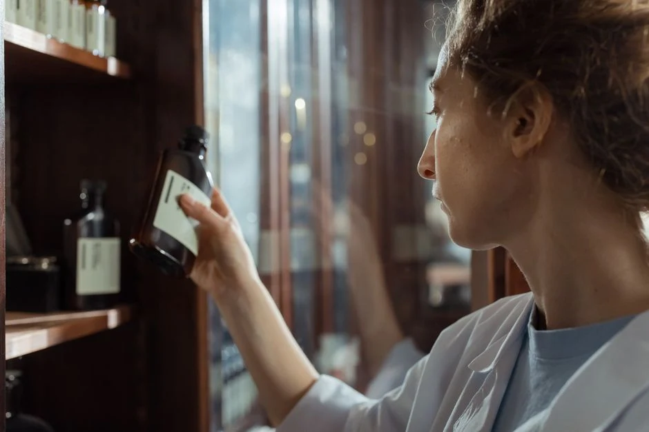 Pharmacist reading the label of a medicine bottle taken from a shelf
