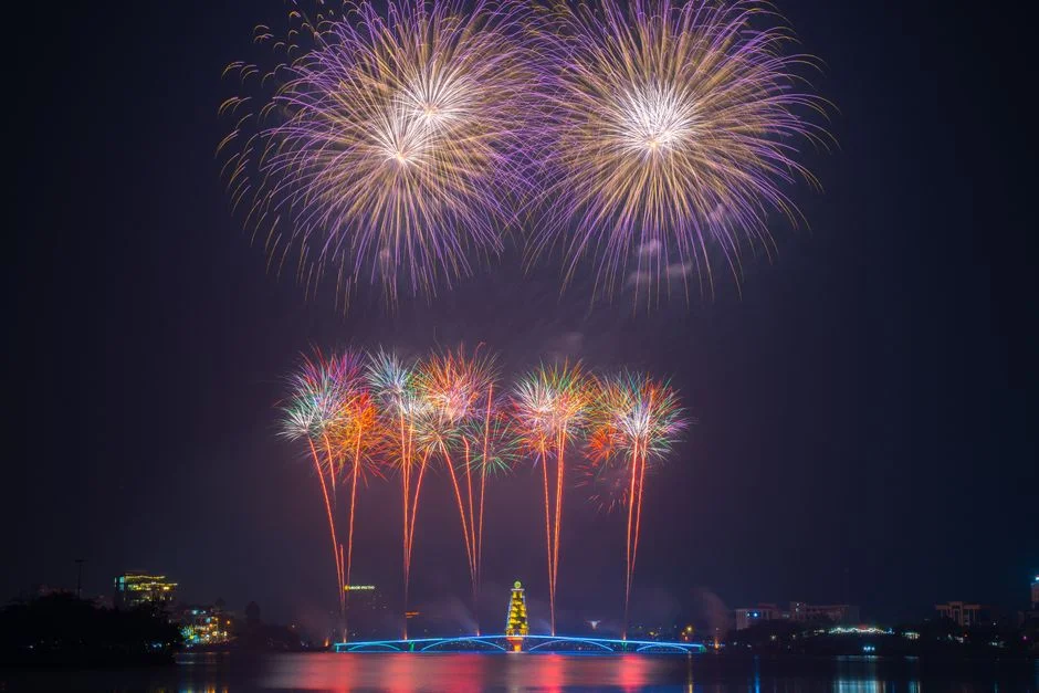 Fireworks over a Vietnamese river at midnight reflecting in the water