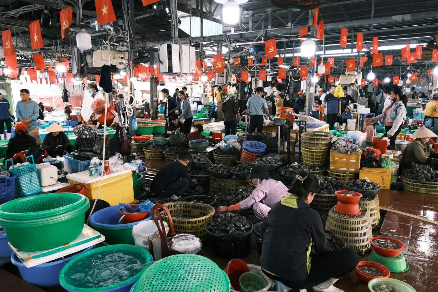 Vendors sorting shellfish in baskets inside a covered seafood market
