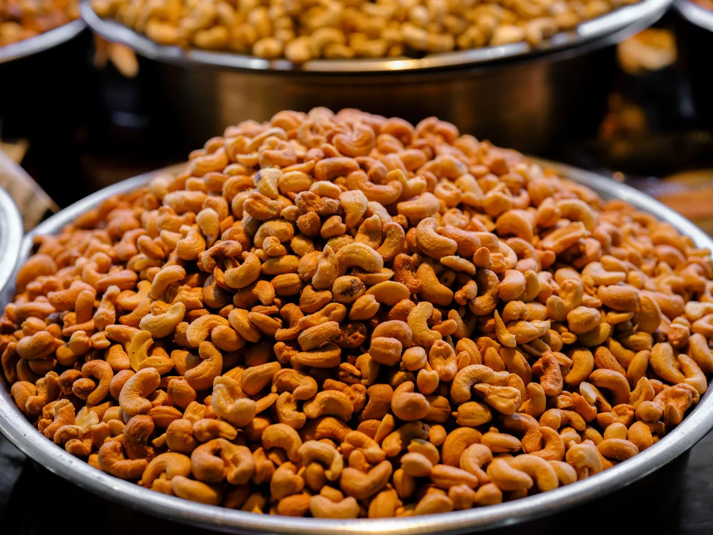 Steel bowls piled with roasted salted cashews at a market stall