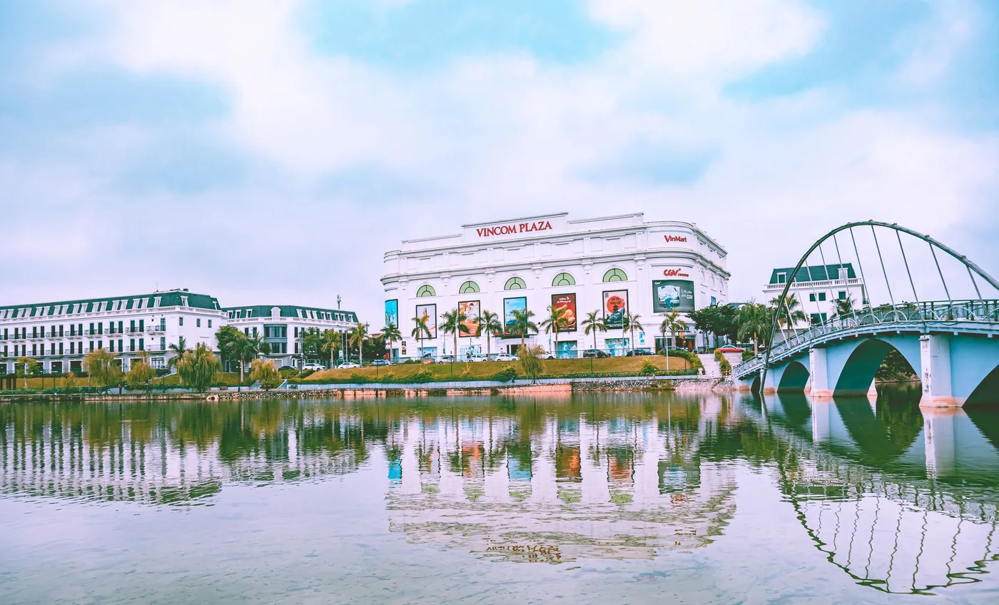 White Vincom Plaza building with a cinema sign across a lake