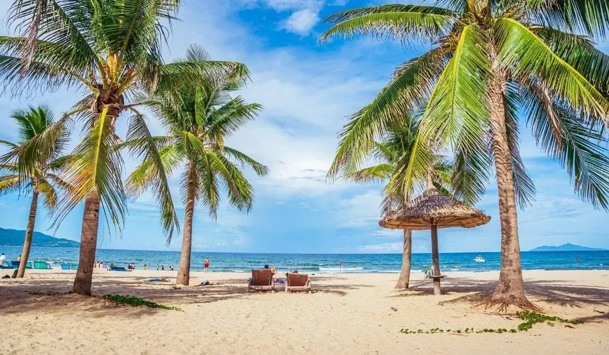 Palm trees and a thatched umbrella on a sandy Nha Trang beach