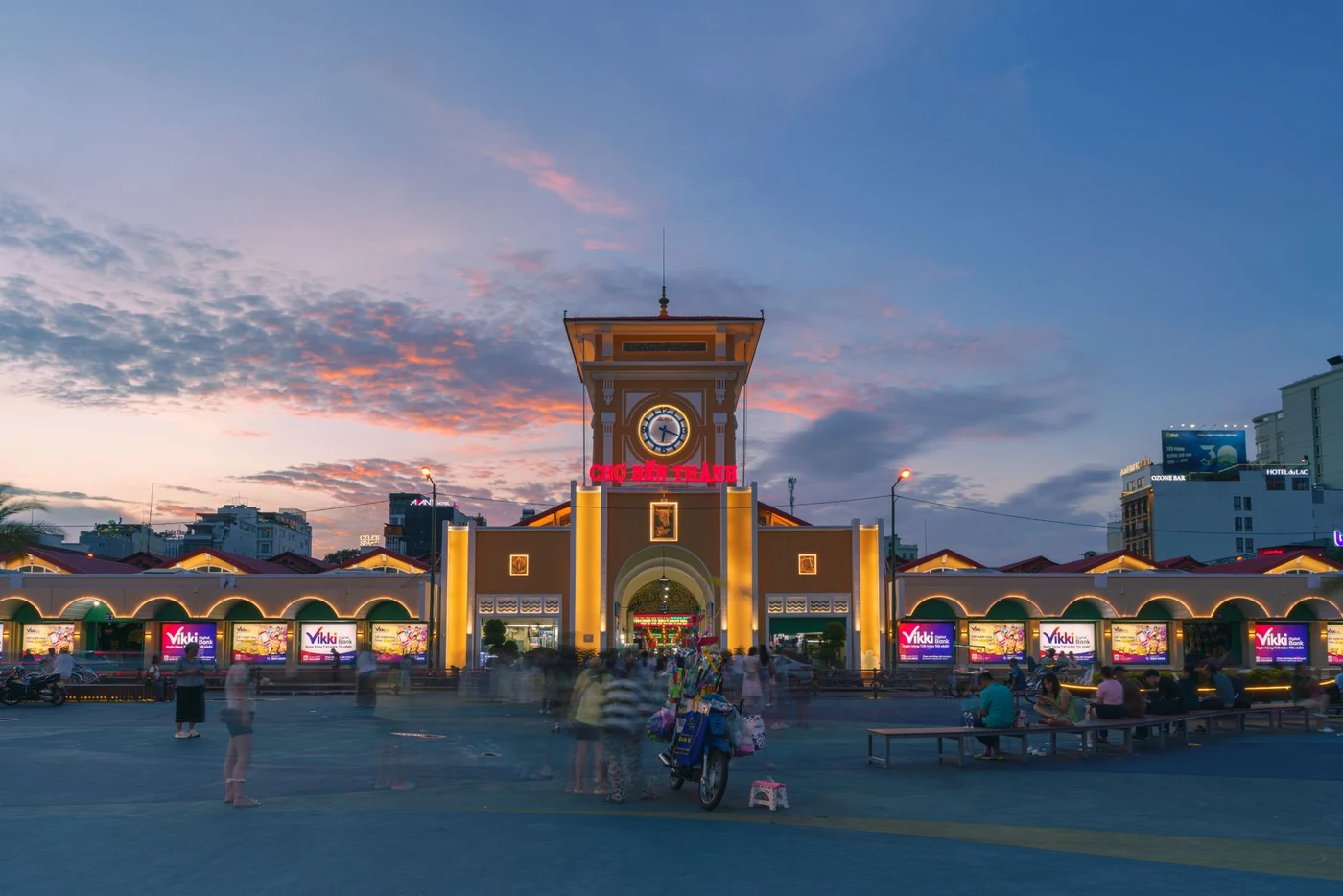 Illuminated clock tower entrance of Ben Thanh Market glowing at dusk