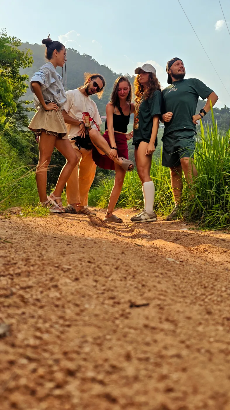 Group of friends laughing together on a dirt trail at sunset