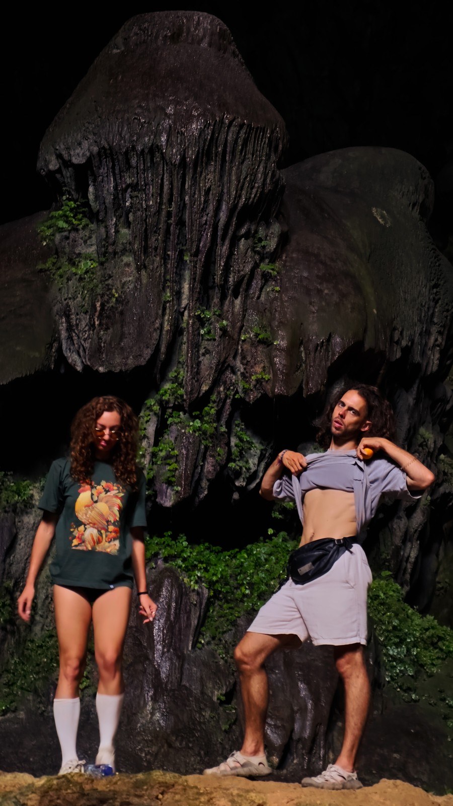 Two travelers exploring a dark limestone cave in Ninh Binh