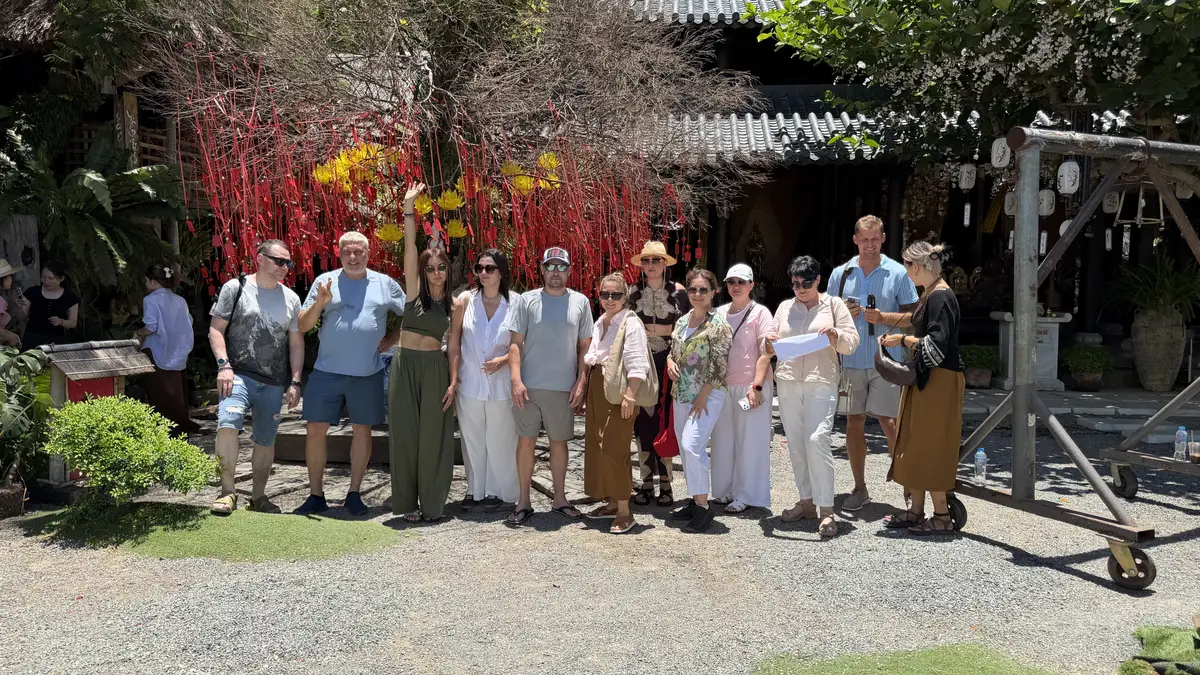 Tour group in a courtyard with a wishing tree hung with red ribbons