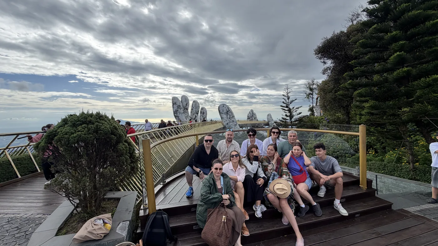 Tour group posing on a bridge held up by giant stone hands