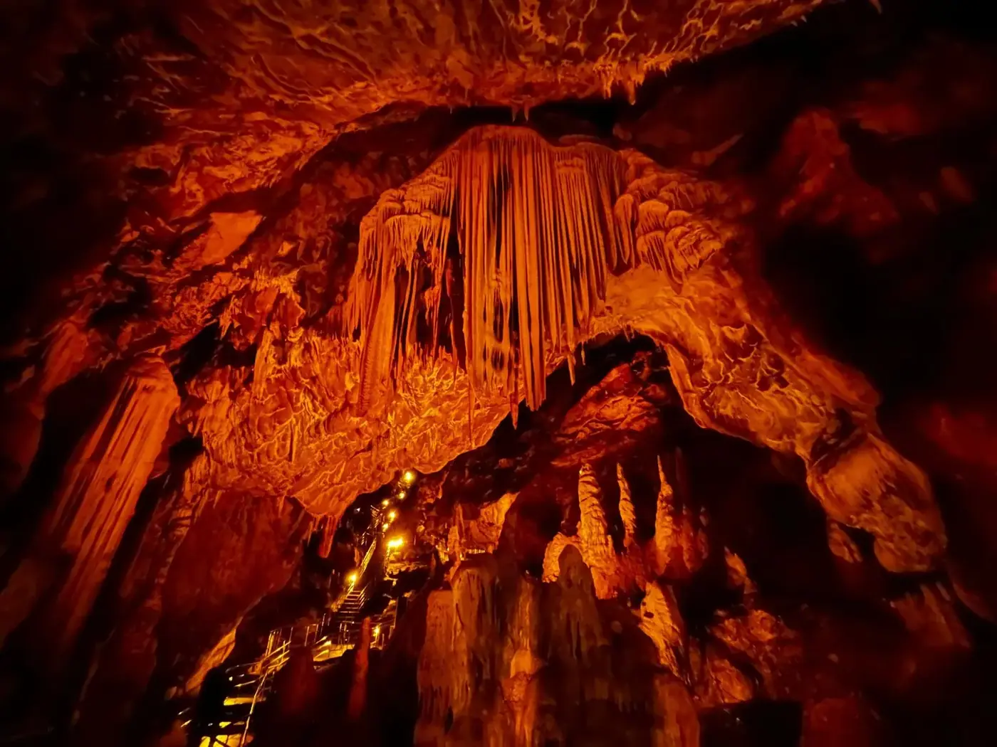 A lit show-cave interior with a wooden tourist walkway and stairs