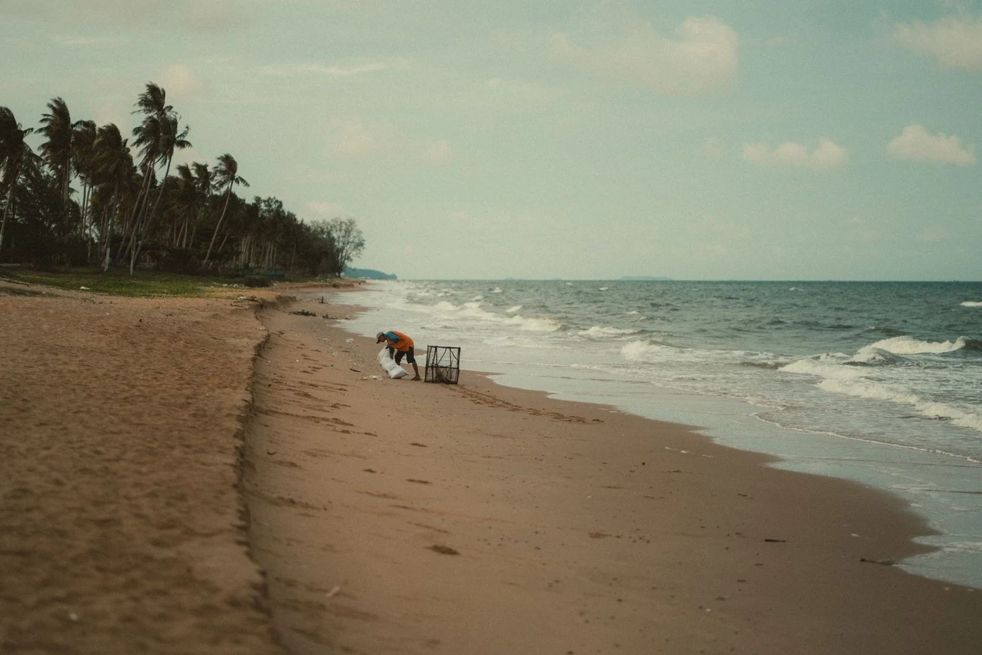 Surf rolling onto an empty sandy shore in windy weather