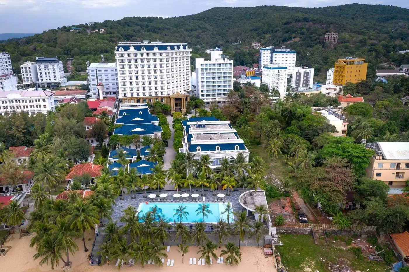 Aerial view of a beachfront hotel with a pool among palm trees
