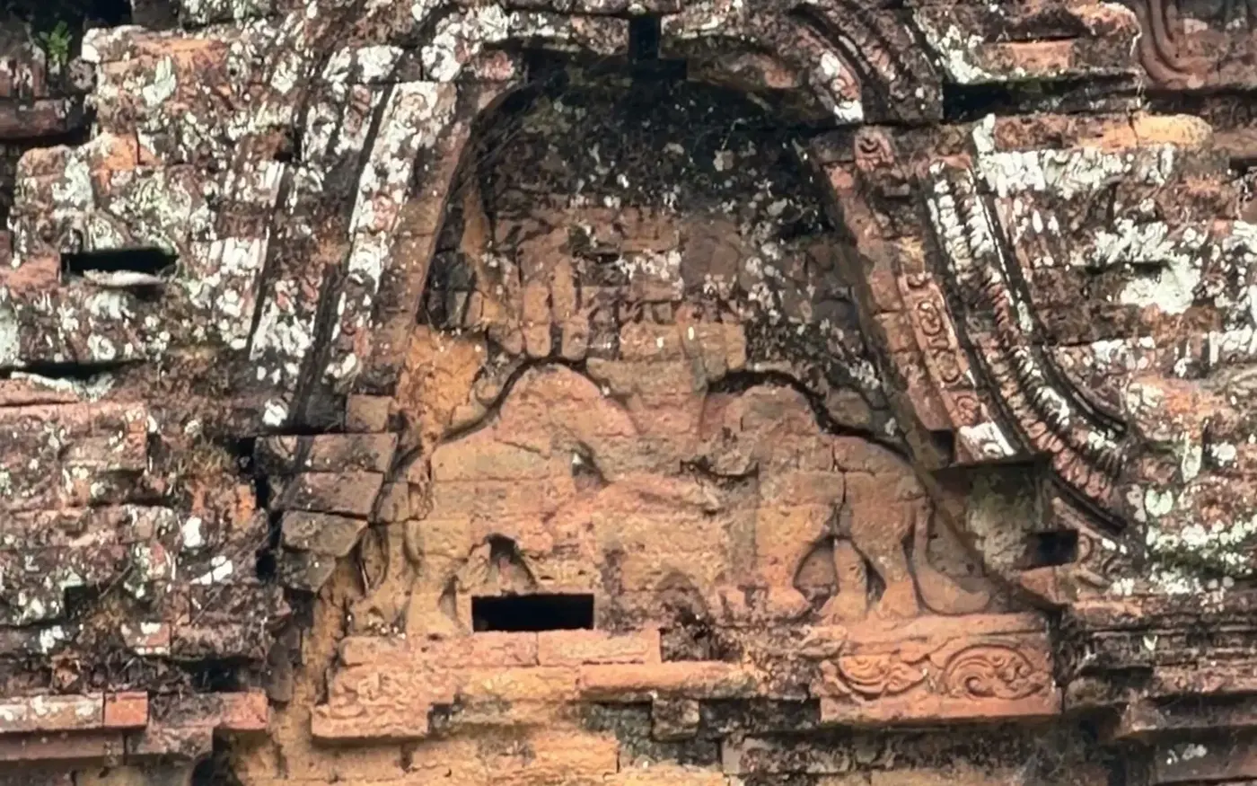 Close view of a Cham brick tower with a stone-framed window and carved niche