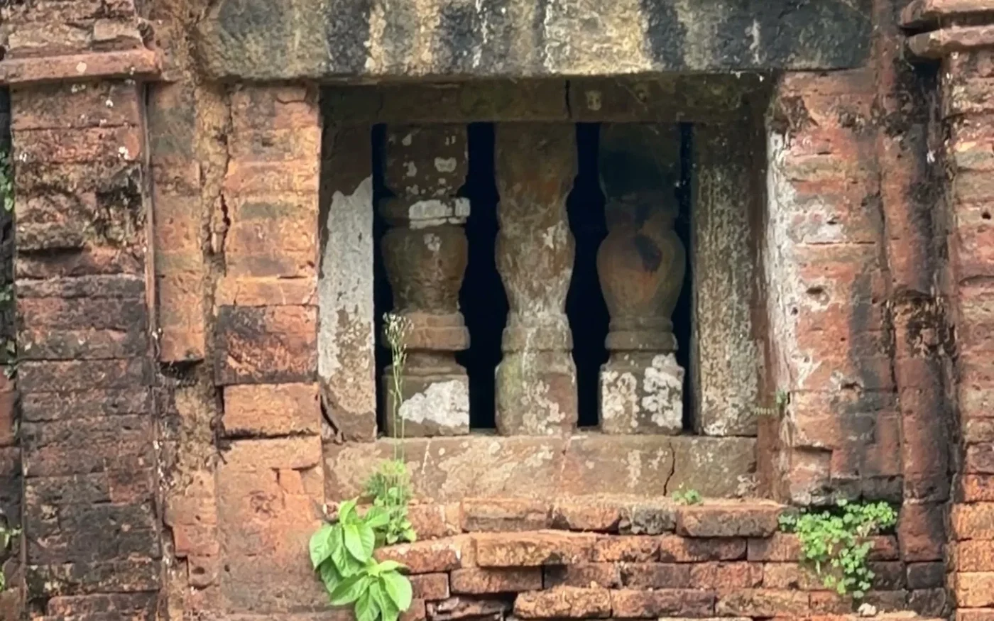 Brick wall of a Cham tower with a stone-balustrade window and carved relief