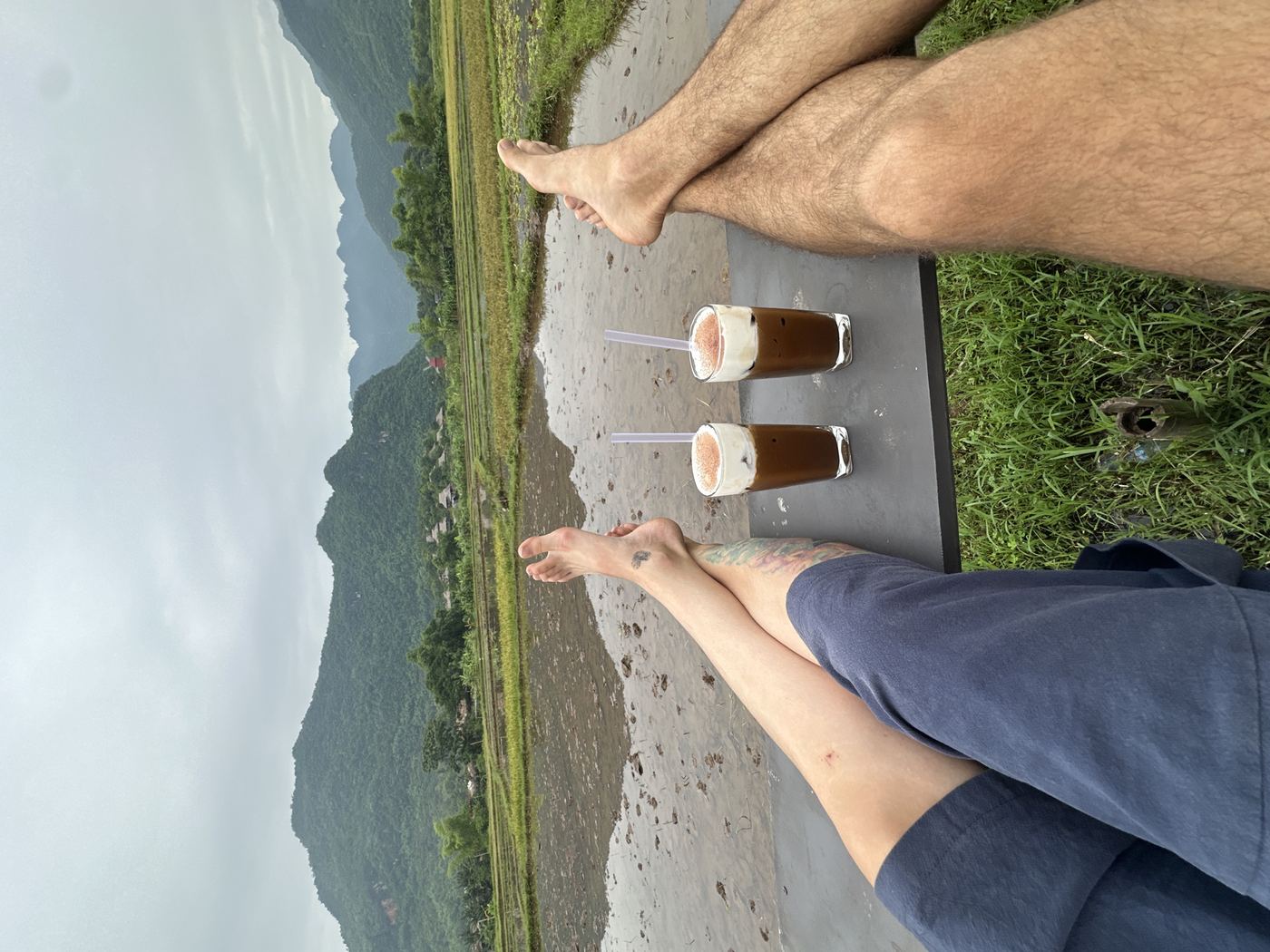 Mai Chau rice terraces valley — two travelers on ridge above flat valley with white rice fields below