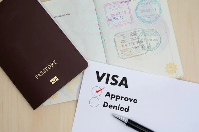 Passport with stamps next to a visa form marked approved and denied